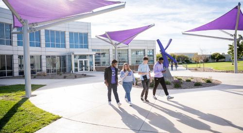 Students walking on the K-State Salina campus in front of the K sculpture.