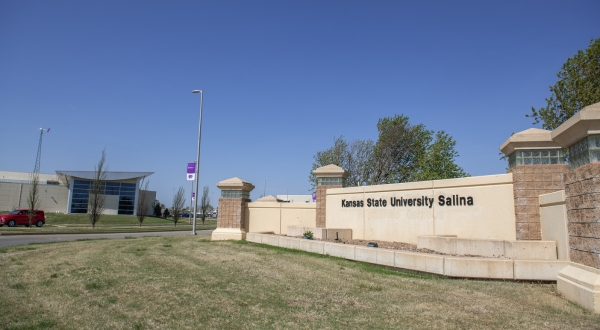 The front gate at K-State Salina on a sunny day with the Student Life Center and K-State Salina flag in the background.