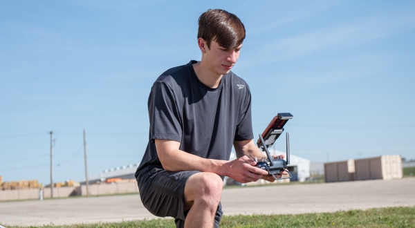 A UAS student studies a remote control that is collecting data during a flight of a drone.