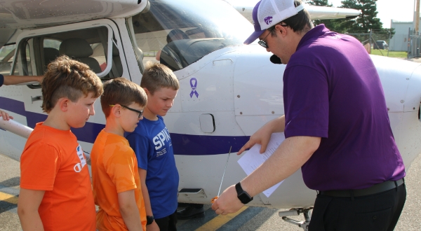 A K-State Salina aviation student shows the parts of an aircraft to youth participating in the campus's Aviation Fixation youth program.