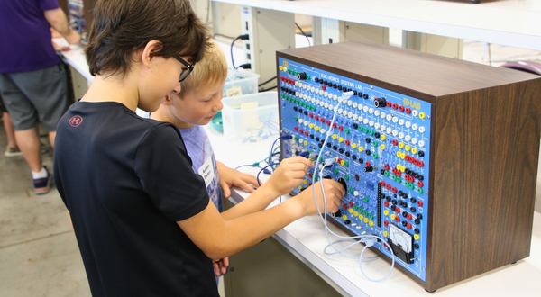 Two youth campers enjoy a hands-on activity with an aviation electronics learning device at K-State Salina.