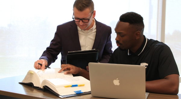 An instructor and learner look over a large instruction manual in K-State Salina's technical writing professional education course.