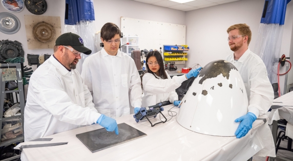 An image of a professor instructing students how to fix a broken aircraft part through composites at the K-State Salina campus.