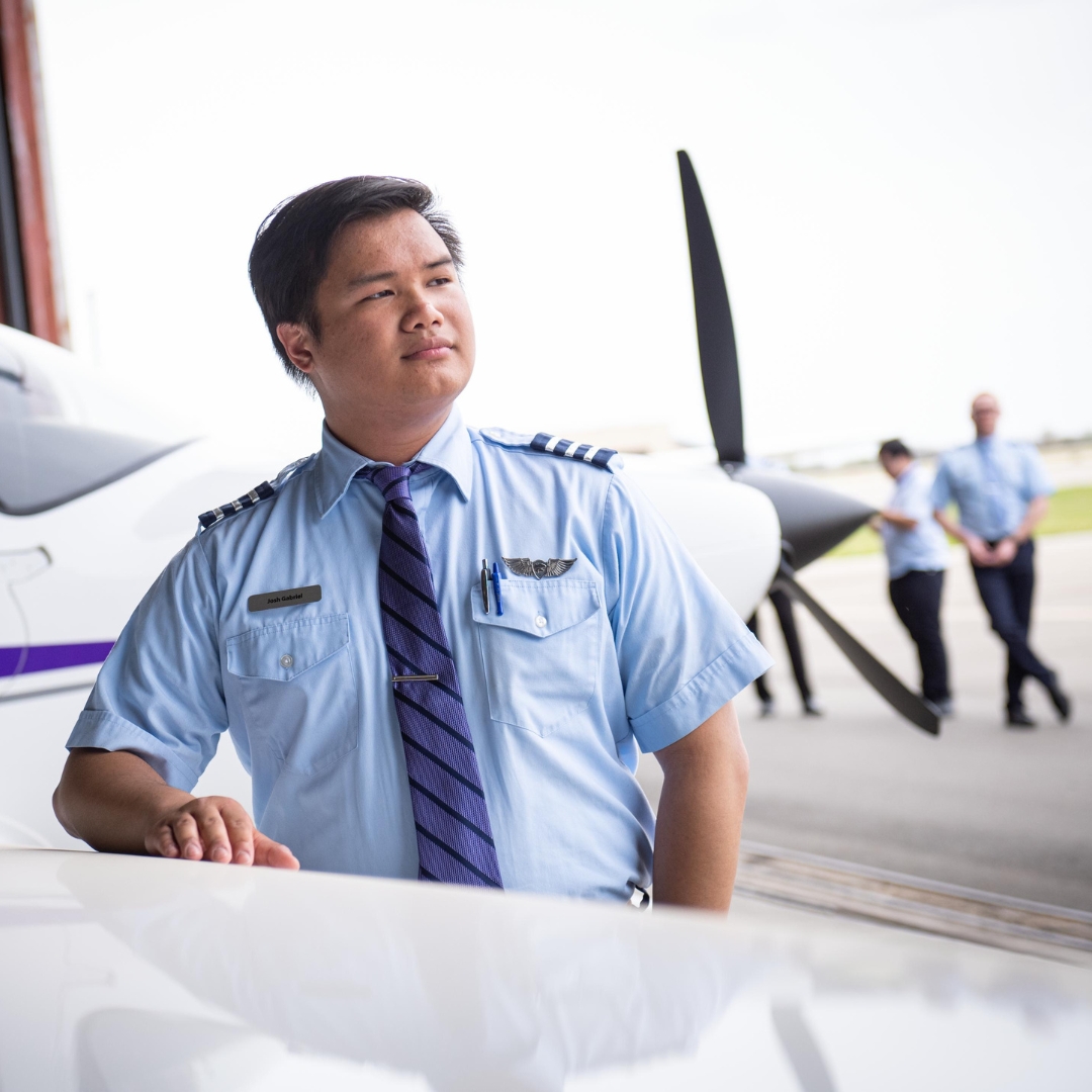 Student standing beside airplane