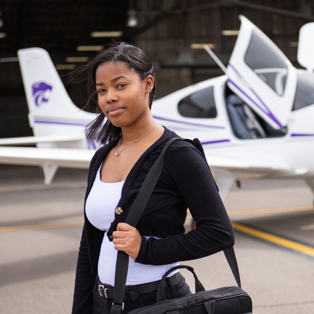 Student in suit standing in front of airplane