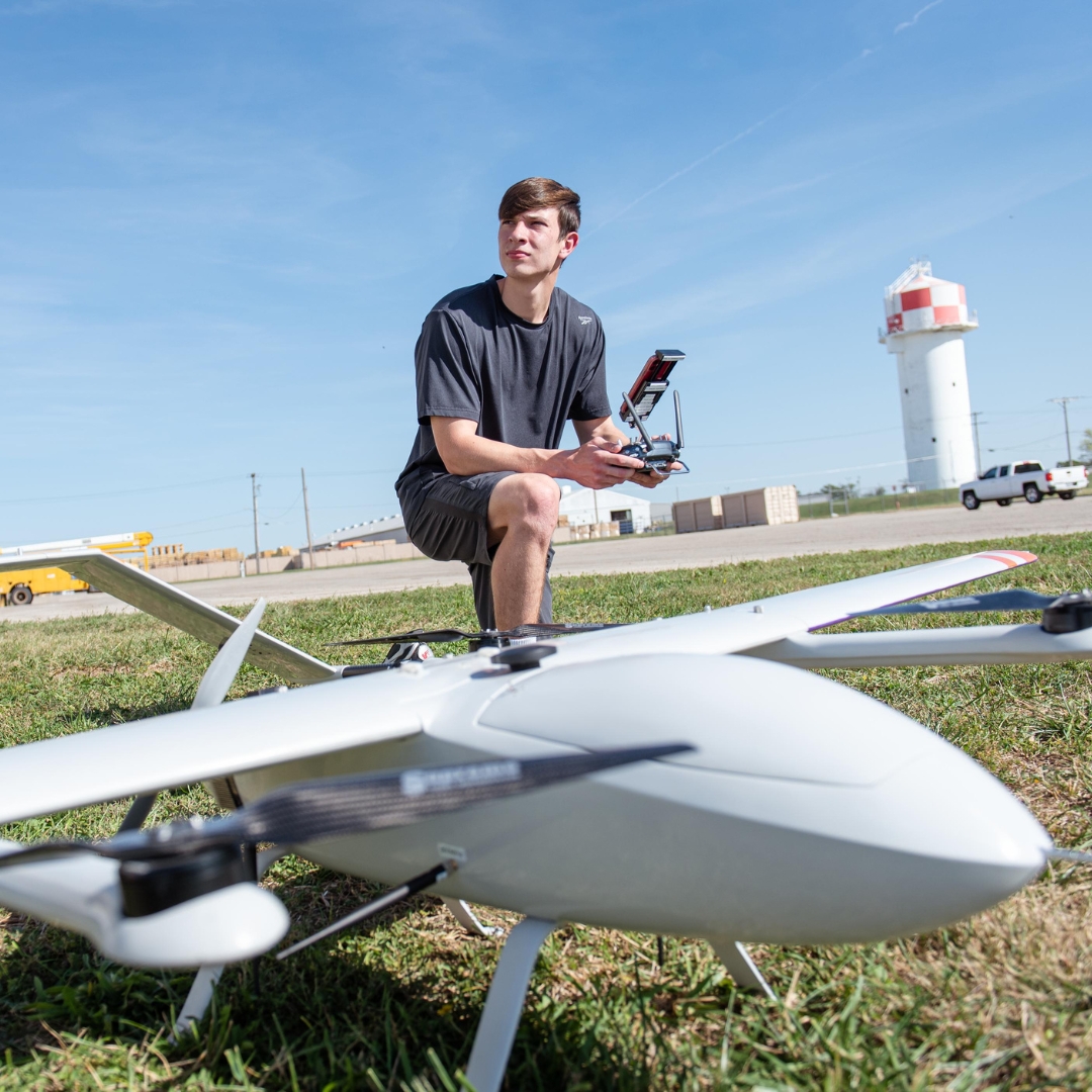 Student kneeling beside UAS drone