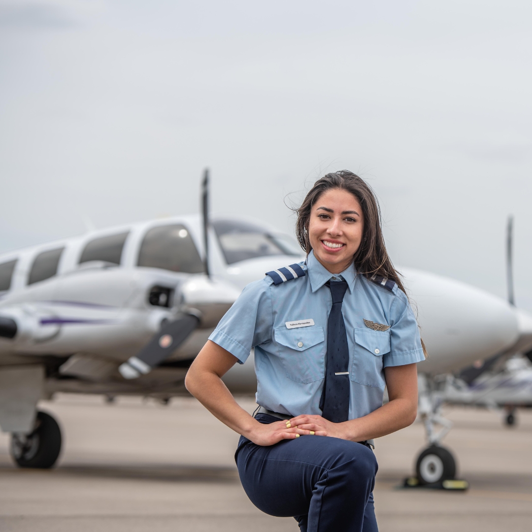 Female pilot kneeling in front of plane